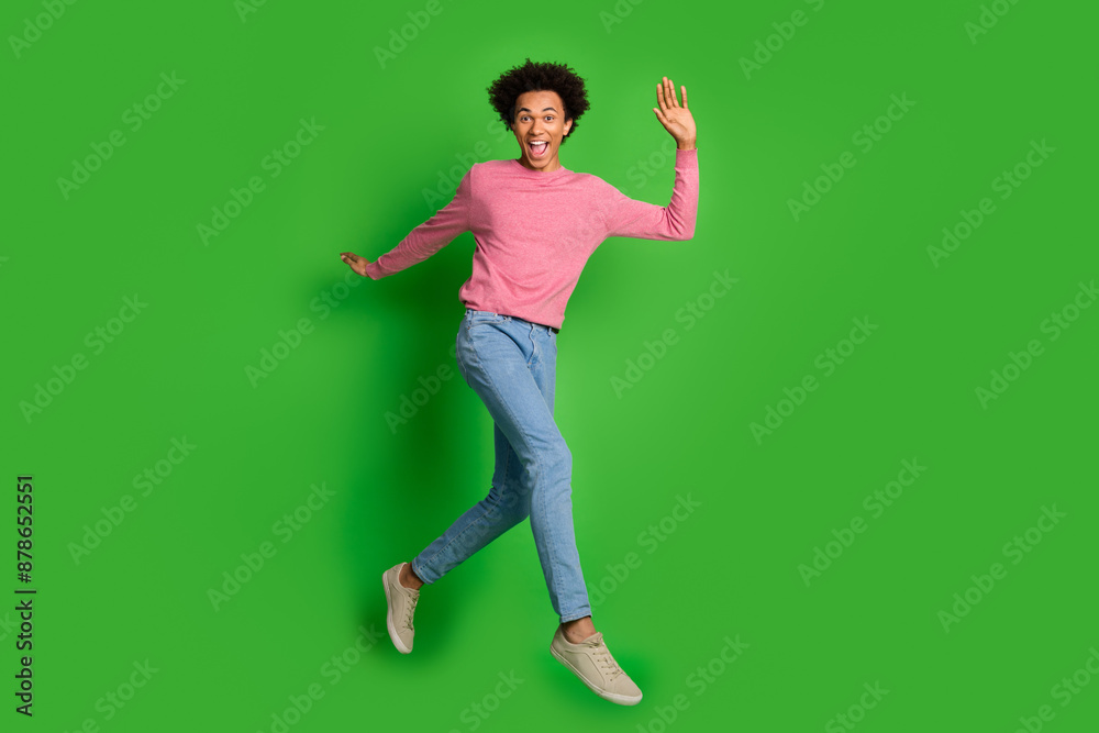 Full length photo of handsome good mood guy wear pink sweater jumping high running emtpy space isolated green color background Full length photo of handsome good mood guy wear pink sweater jumping high running emtpy space isolated green color background