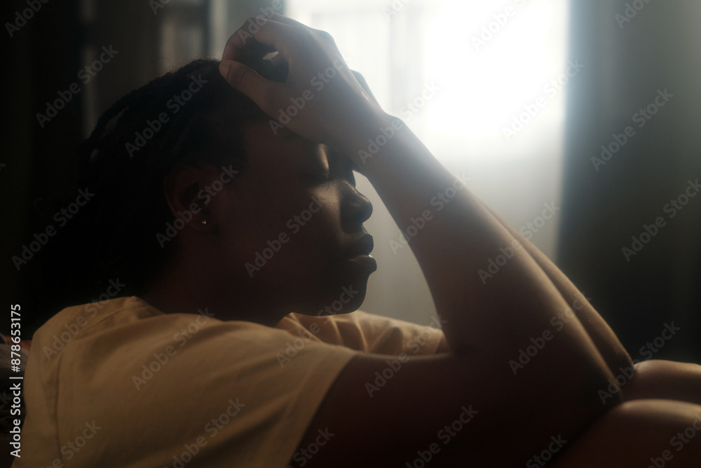 Side view of young desperate woman keeping her hands on head and eyes closed while suffering from pain caused by PTSD Side view of young desperate woman keeping her hands on head and eyes closed while suffering from pain caused by PTSD