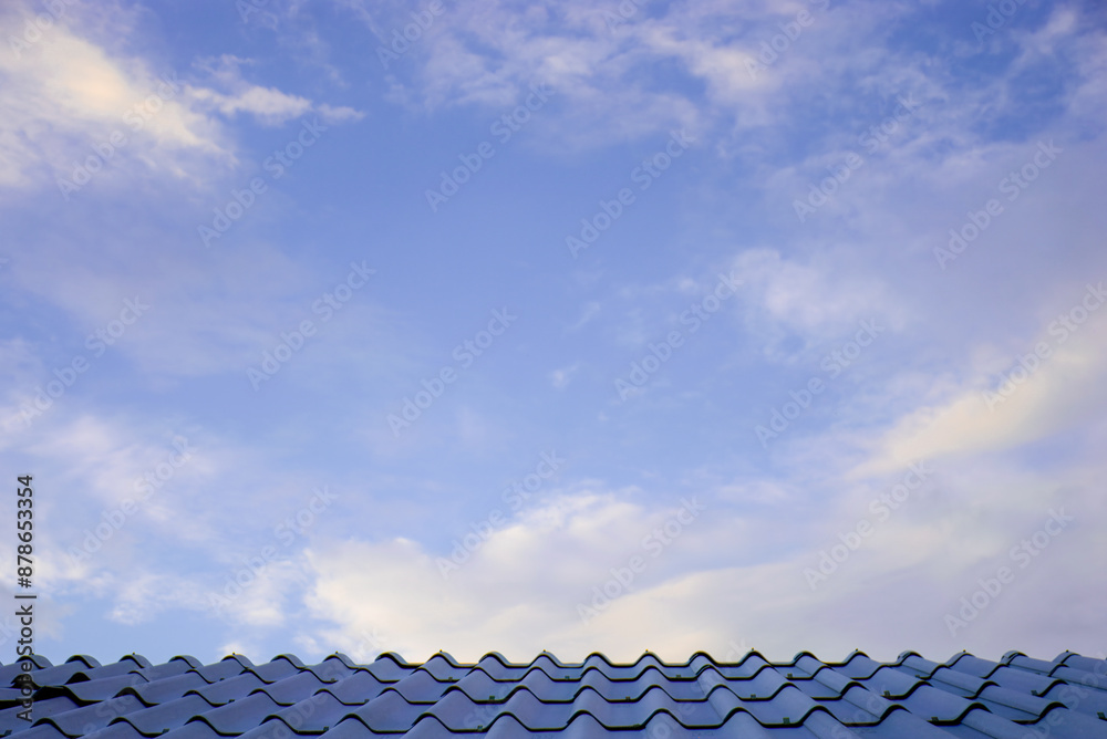 Blue sky with white clouds above a tiled roof Blue sky with white clouds above a tiled roof
