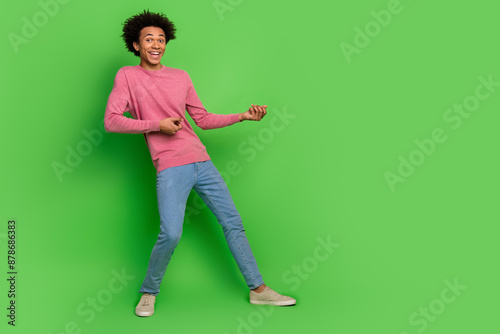 Full length photo of attractive funny guy wear pink sweater pulling emtpy space isolated green color background