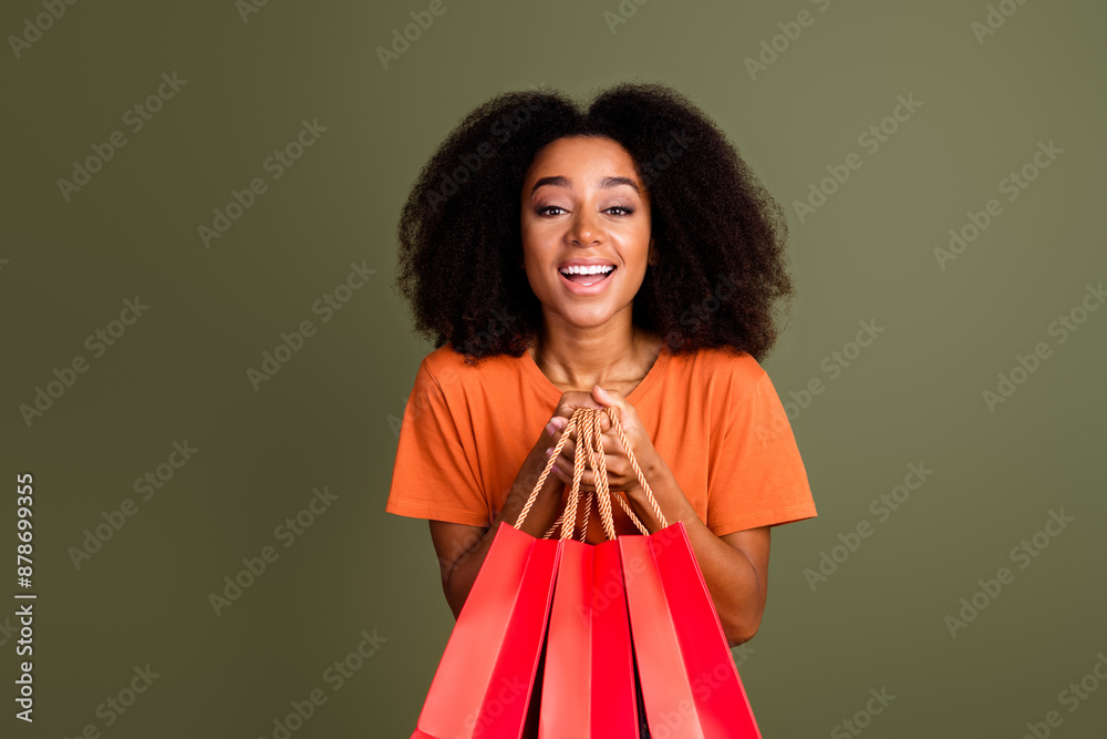 Photo of shiny attractive lady dressed orange outfit holding bargains empty space isolated khaki color background Photo of shiny attractive lady dressed orange outfit holding bargains empty space isolated khaki color background