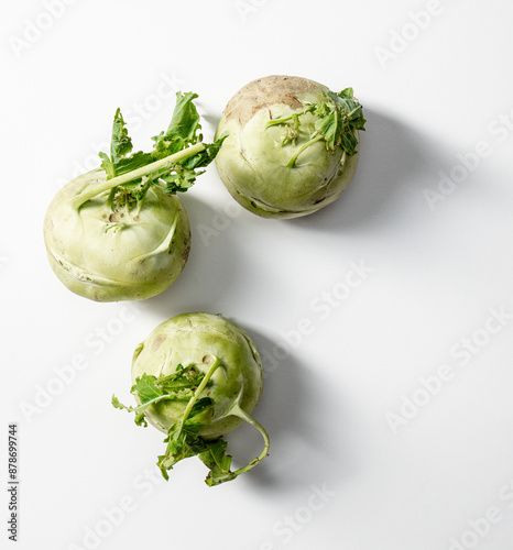 three fresh kohlrabi with green leaves