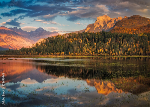 Dramatic golden hour sky reflecting on serene mountain lake in autumn