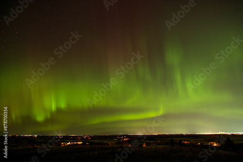 Aurora borealis displaying vibrant green lights over cityscape