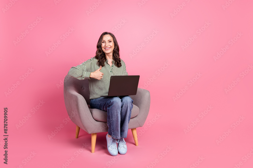 Full length photo of adorable lovely woman wear striped shirt working modern gadget thumb up empty space isolated pink color background Full length photo of adorable lovely woman wear striped shirt working modern gadget thumb up empty space isolated pink color background
