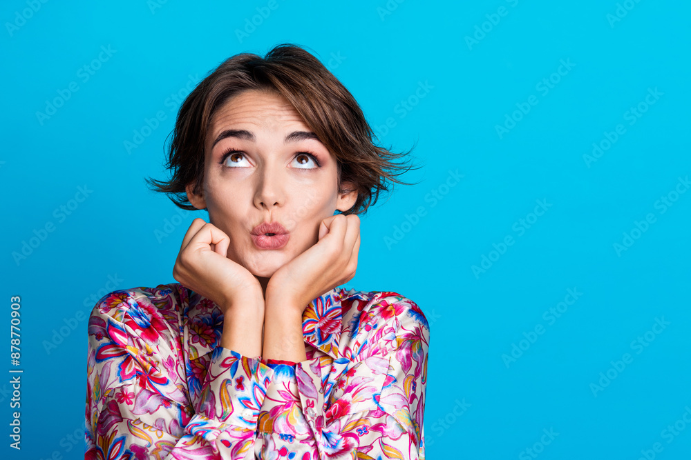 Photo of sweet dreamy pretty girl wear stylish clothes two arms touch cheeks look up novelty empty space isolated on blue color background