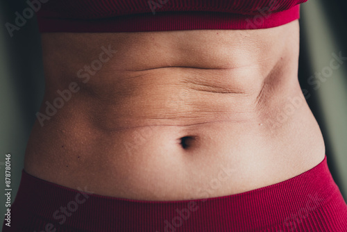 Cropped unretouched photo of girl belly with fat folds body positive concept isolated green linen background photo