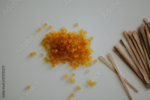 yellow depilatory wax balls and wooden stirring sticks in the white background  photo