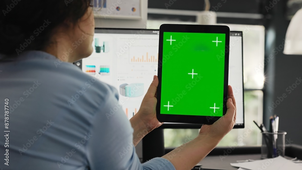 Office worker examines greenscreen layout in coworking space, working on business operations and looking at isolated chromakey display. Woman holding tablet with blank copyspace. Office worker examines greenscreen layout in coworking space, working on business operations and looking at isolated chromakey display. Woman holding tablet with blank copyspace.
