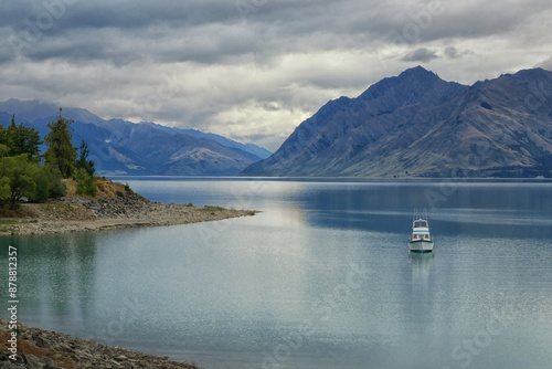 Yacht anchored by the shore surrounded by mountains