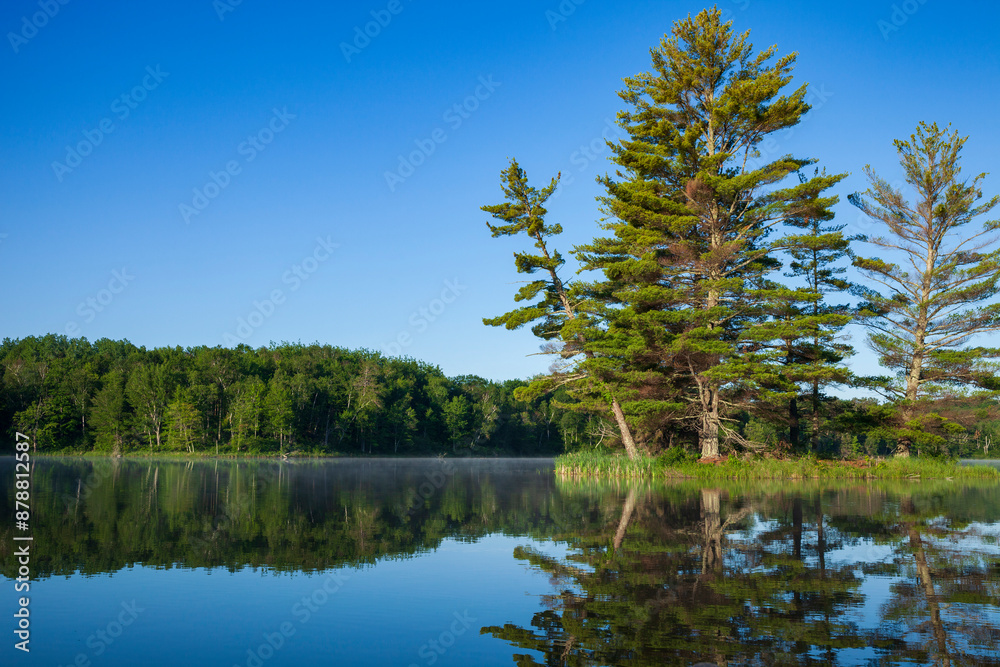 Beautiful calm blue lake and island with pine trees under a clear sky on a summer morning in northern Minnesota Beautiful calm blue lake and island with pine trees under a clear sky on a summer morning in northern Minnesota
