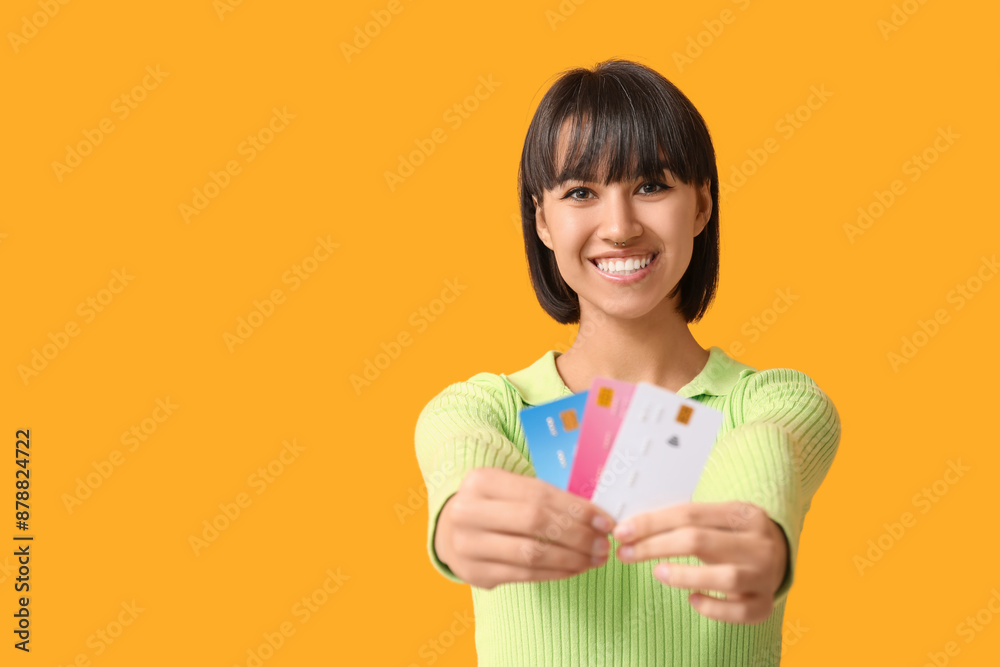 Happy young woman with credit cards on yellow background Happy young woman with credit cards on yellow background