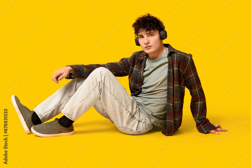 Handsome young man in stylish clothes and headphones on yellow background Handsome young man in stylish clothes and headphones on yellow background