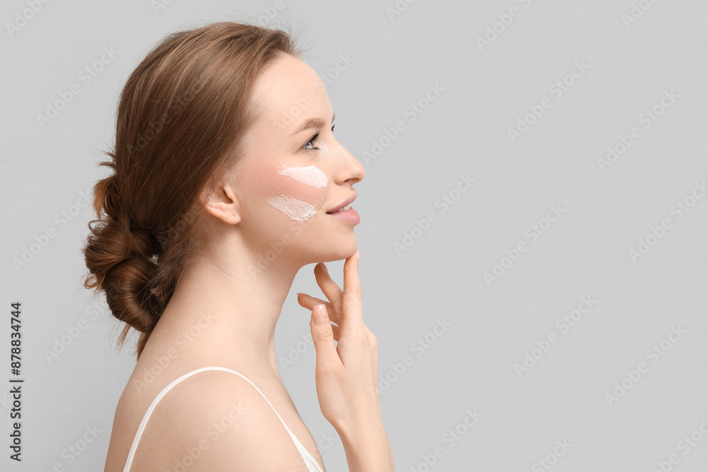 Thoughtful young woman with cream on grey background Thoughtful young woman with cream on grey background