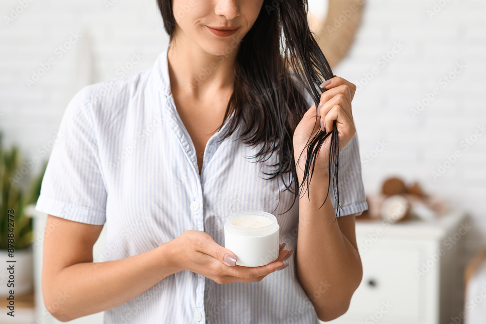 Beautiful young woman applying coconut oil onto hair in bathroom Beautiful young woman applying coconut oil onto hair in bathroom