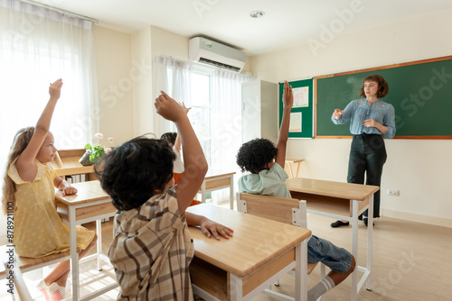 Adorable student learn with teacher in classroom at elementary school. 