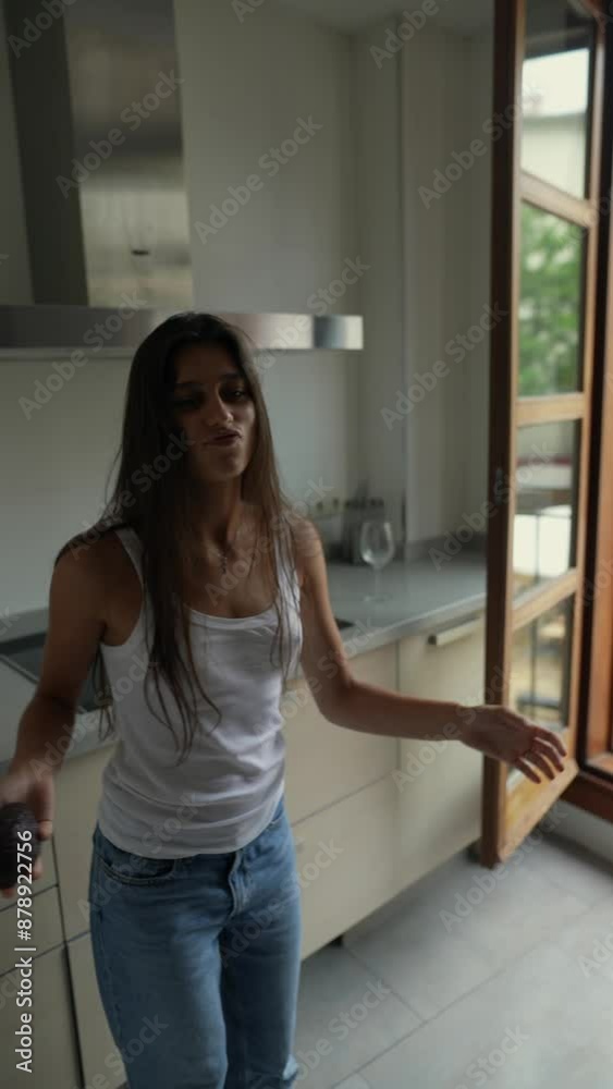A young woman happily tossing an avocado in a stylish kitchen with an open window, exuding peace A young woman happily tossing an avocado in a stylish kitchen with an open window, exuding peace