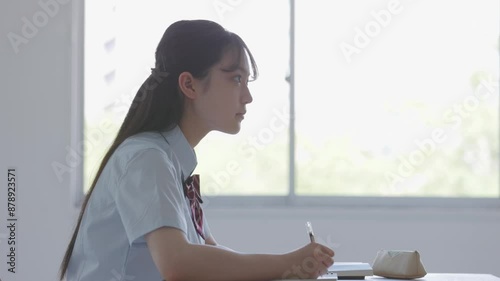 学校の教室で授業を受ける女子高校生