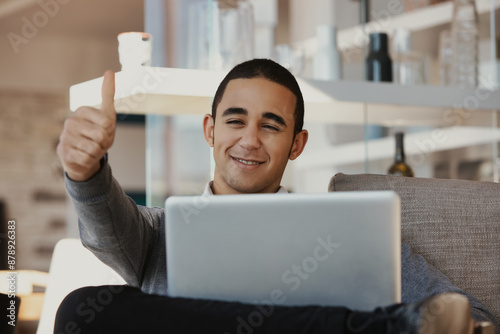 Young entrepreneur smiling and giving thumbs up while working at