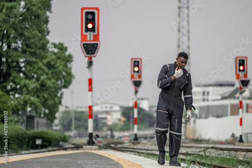 A railway signal maintainer communicates via radio while walking along the tracks © SpaceOak