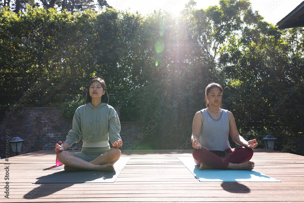 Happy asian female friends practicing yoga and meditating in garden at home Happy asian female friends practicing yoga and meditating in garden at home