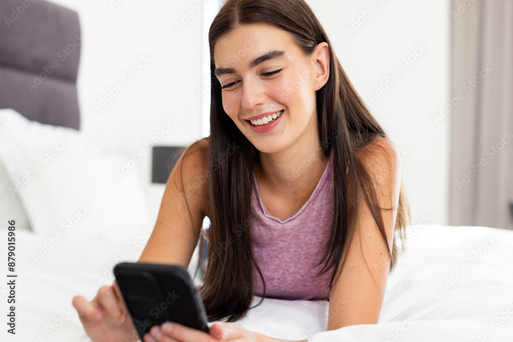 Teenage Caucasian girl smiles while using her smartphone in a home setting Teenage Caucasian girl smiles while using her smartphone in a home setting