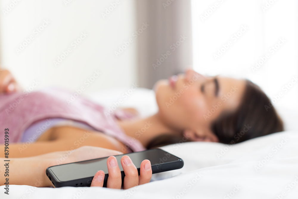 Teenage Caucasian girl lies on a pretty bed holding a smartphone Teenage Caucasian girl lies on a pretty bed holding a smartphone