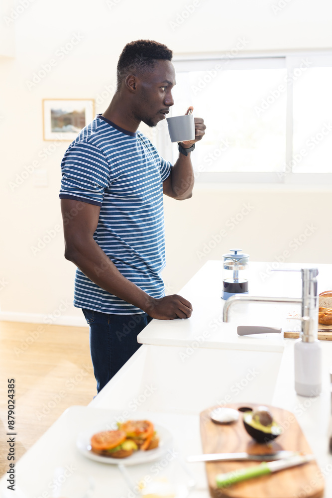 African american man preapring food drinking coffee in kitchen, copy space