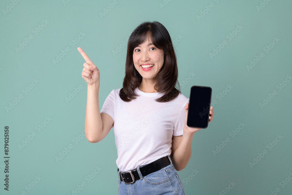 Woman holding phone and looking surprised, dressed in white t-shirt and jeans.