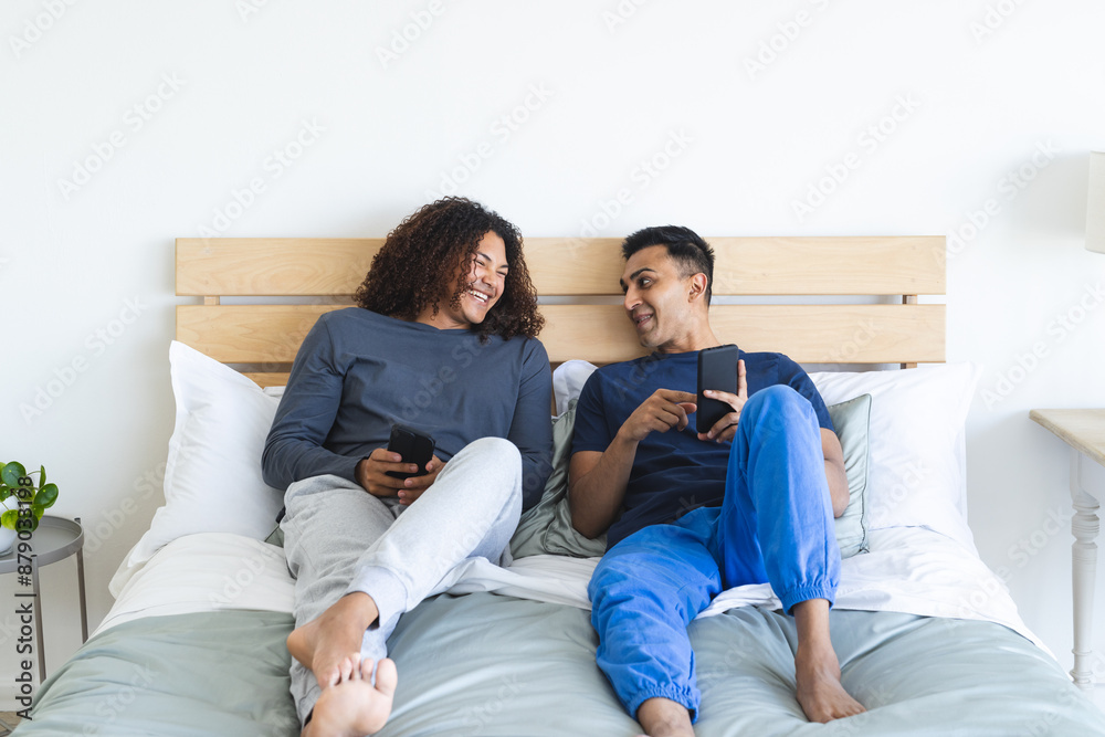 Gay biracial couple relaxes in a cozy bedroom setting Gay biracial couple relaxes in a cozy bedroom setting