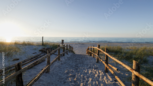 Obraz na płótnie Sandy entrance to the beach. Sunset. Wooden balustrades. Footprints in the sand. Dunes covered with grass. Slajszewo, Poland. Baltic Sea w salonie