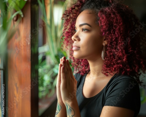 A woman with red hair and a black shirt is praying. AI.