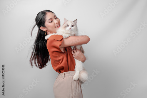 Cuadro en lienzo Pretty young Asian woman in a brown shirt is holding a white ragdoll cat and raising it high