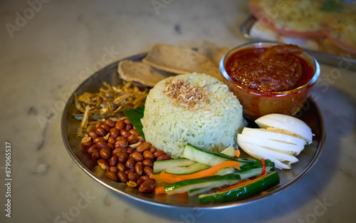 Delicious nasi lemak standing on table with chicken curry and condiments photo