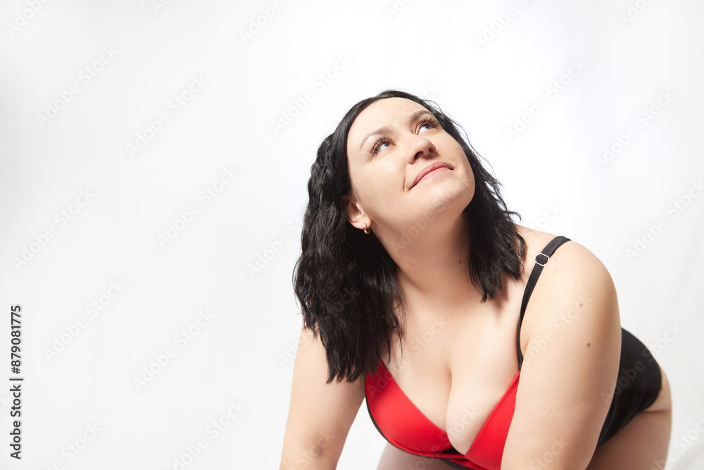 Portrait of attractive dreamy thick woman in red black swimsuit posing on white background. Body positive, photo shoot, selfie. Funny plus size model Portrait of attractive dreamy thick woman in red black swimsuit posing on white background. Body positive, photo shoot, selfie. Funny plus size model