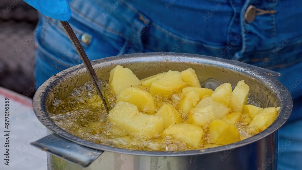 Potatoes in boiling oil. Close-up of potatoes frying in hot oil. Potato pieces surrounded by bubbles from boiling oil during cooking. French fries. Selective focus. Potatoes in boiling oil. Close-up of potatoes frying in hot oil. Potato pieces surrounded by bubbles from boiling oil during cooking. French fries. Selective focus.