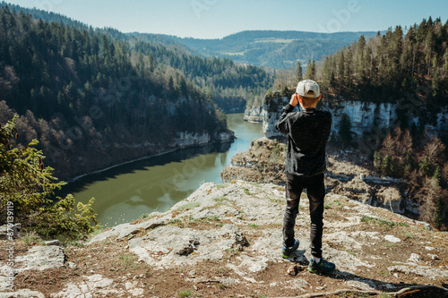 Boy hiking, watching River Doubs, Switzerland, from a cliff viewpoint