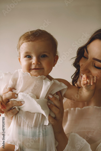 Baby playing with mother. Woman hugs her cute smiling baby girl photo