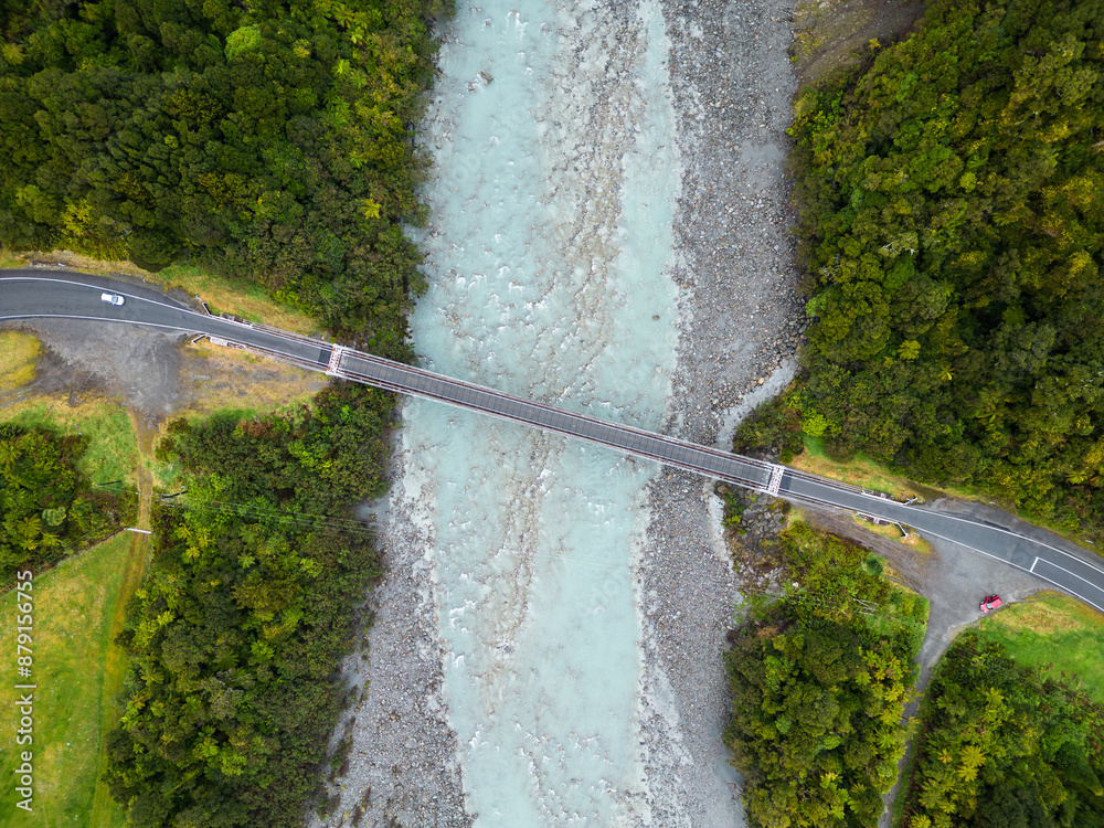 Fox Glacier, New Zealand: Overhead drone view of a car crossing the bridge over the Karangarua river near Fox glacier town in New Zealand south island wild west coast.