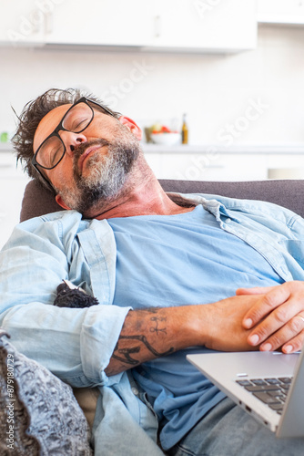 Concept of necessity of having a rest while working. Tired exhausted manager clothed in formal-wear is sleeping on a sofa in his modern office