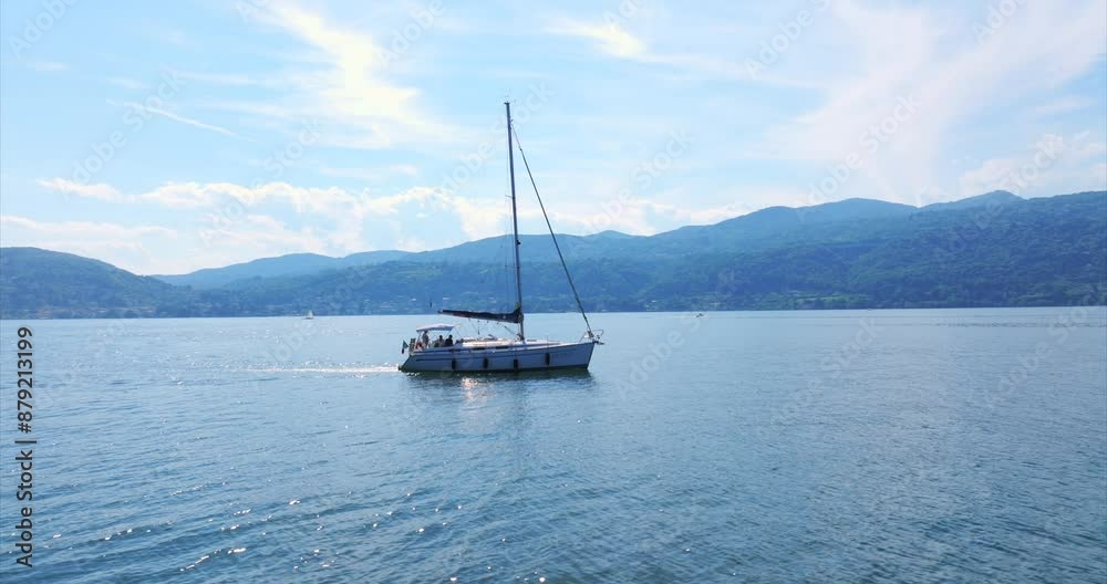 Aerial View Of Sailboat peacefully sails on lake maggiore, surrounded by majestic mountains on a sunny day, offering a picturesque view of nature for leisure and relaxation. orbit motion shot Aerial View Of Sailboat peacefully sails on lake maggiore, surrounded by majestic mountains on a sunny day, offering a picturesque view of nature for leisure and relaxation. orbit motion shot
