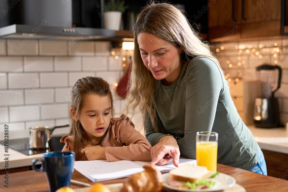 Morning joy in the kitchen: A smiling mother teaches her preschooler the art of writing letters at the table during breakfast. Laughter and learning create a perfect start to the day. Morning joy in the kitchen: A smiling mother teaches her preschooler the art of writing letters at the table during breakfast. Laughter and learning create a perfect start to the day.