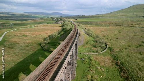 Curved railway track over viaduct bridge with reverse drone flight revealing structure and arches at golden hour. Ribblehead Viaduct, North Yorkshire, England, UK photo