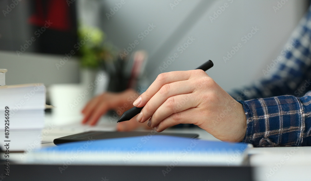 A young designer holds pen from tablet in hand working on new project for customer in field of building construction projects.