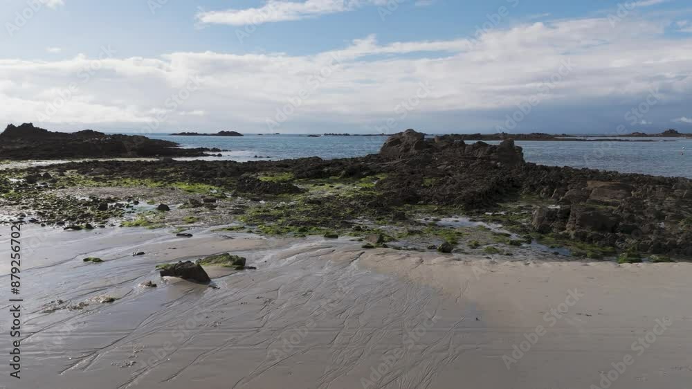 Low drone flight over beach rockpools and rocks at low tide out to sea from Belle Greve Bay Guernsey on bright calm day Low drone flight over beach rockpools and rocks at low tide out to sea from Belle Greve Bay Guernsey on bright calm day