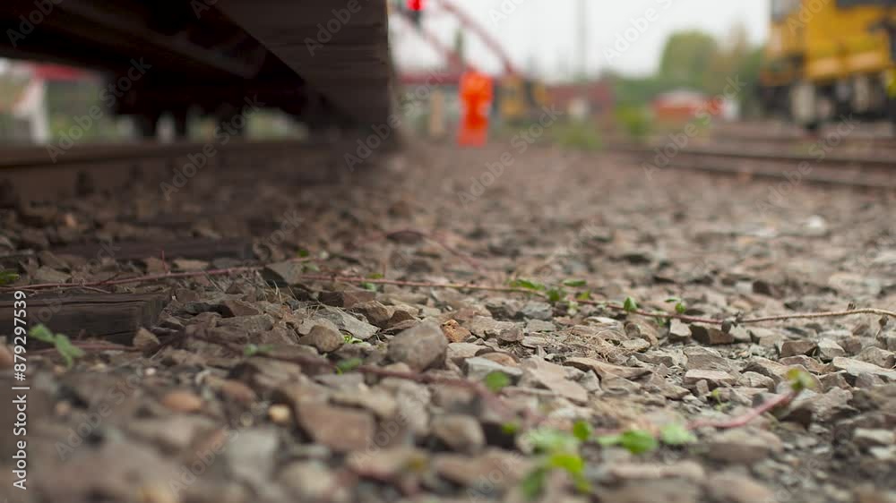 Close-up of a railway switch lever on track with blurred workers in background, daytime Close-up of a railway switch lever on track with blurred workers in background, daytime