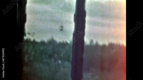 Old rural window view in green forest. Lonely, quiet lifestyle inside village house. No people. Country home surrounded by summer nature. Vintage color film. Family archive. Retro 1960s countryside