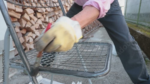 Man using brush to paint an object. Worker in backyard painting a chair
