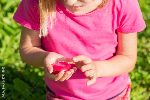 Girl in a pink T-shirt plays with a Tamagotchi toy, popular game, caring for a virtual pet in the 90s. photo