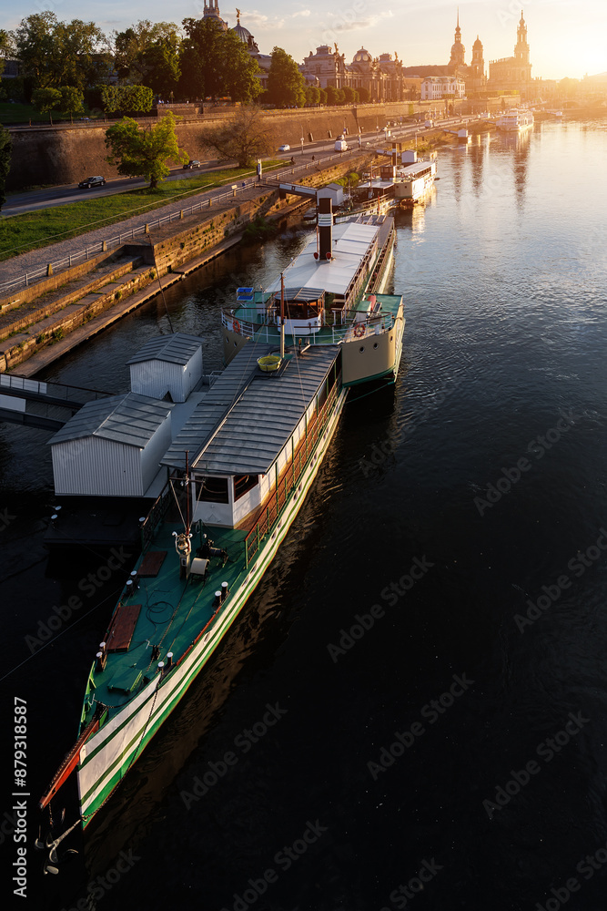 Scenic warm sunset beautiful Dresden city skyline at Elbe River with many steam tourist ship vessel moored at bank. Saxony Germany capital cityscape dusk panoramic view with old Europe architecture Scenic warm sunset beautiful Dresden city skyline at Elbe River with many steam tourist ship vessel moored at bank. Saxony Germany capital cityscape dusk panoramic view with old Europe architecture